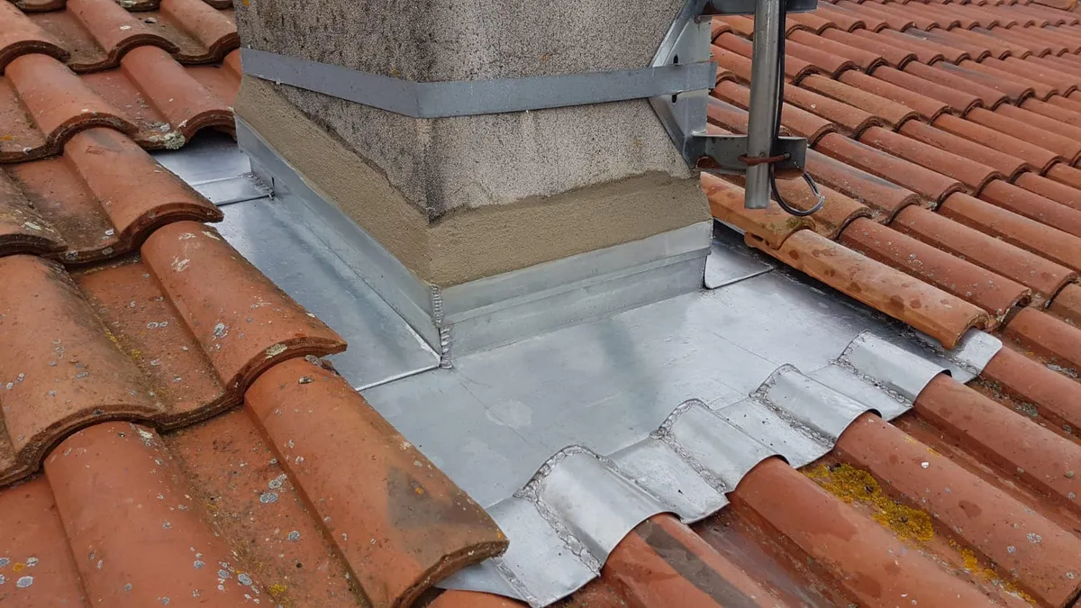 Zinguerie sur-mesure : abergement de cheminée en zinc sur une toiture en tuiles
