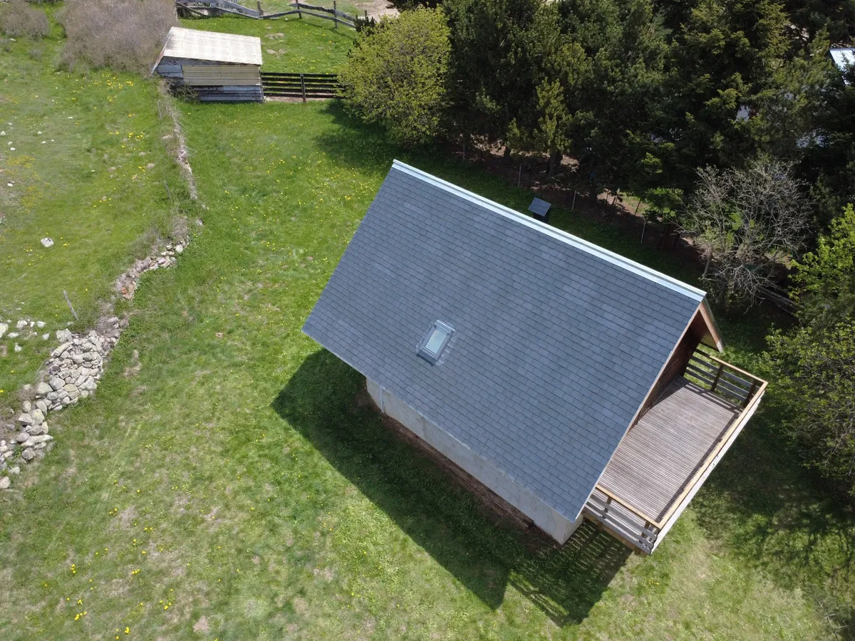 Vue aérienne d'une maison avec toiture grise refaite et terrasse en bois