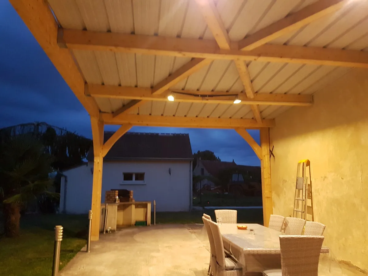 Terrasse couverte à charpente bois éclairée le soir